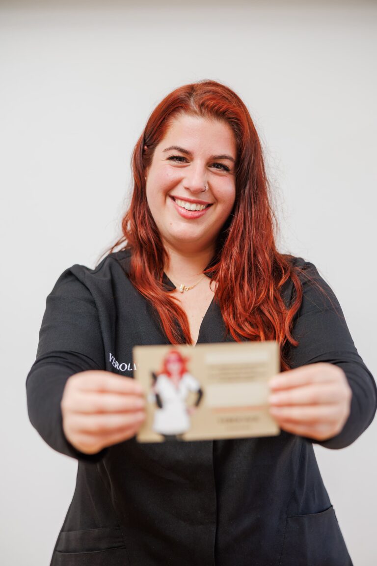 Vero sonriendo mientras sostiene una tarjeta en la mano en Vero Láser.